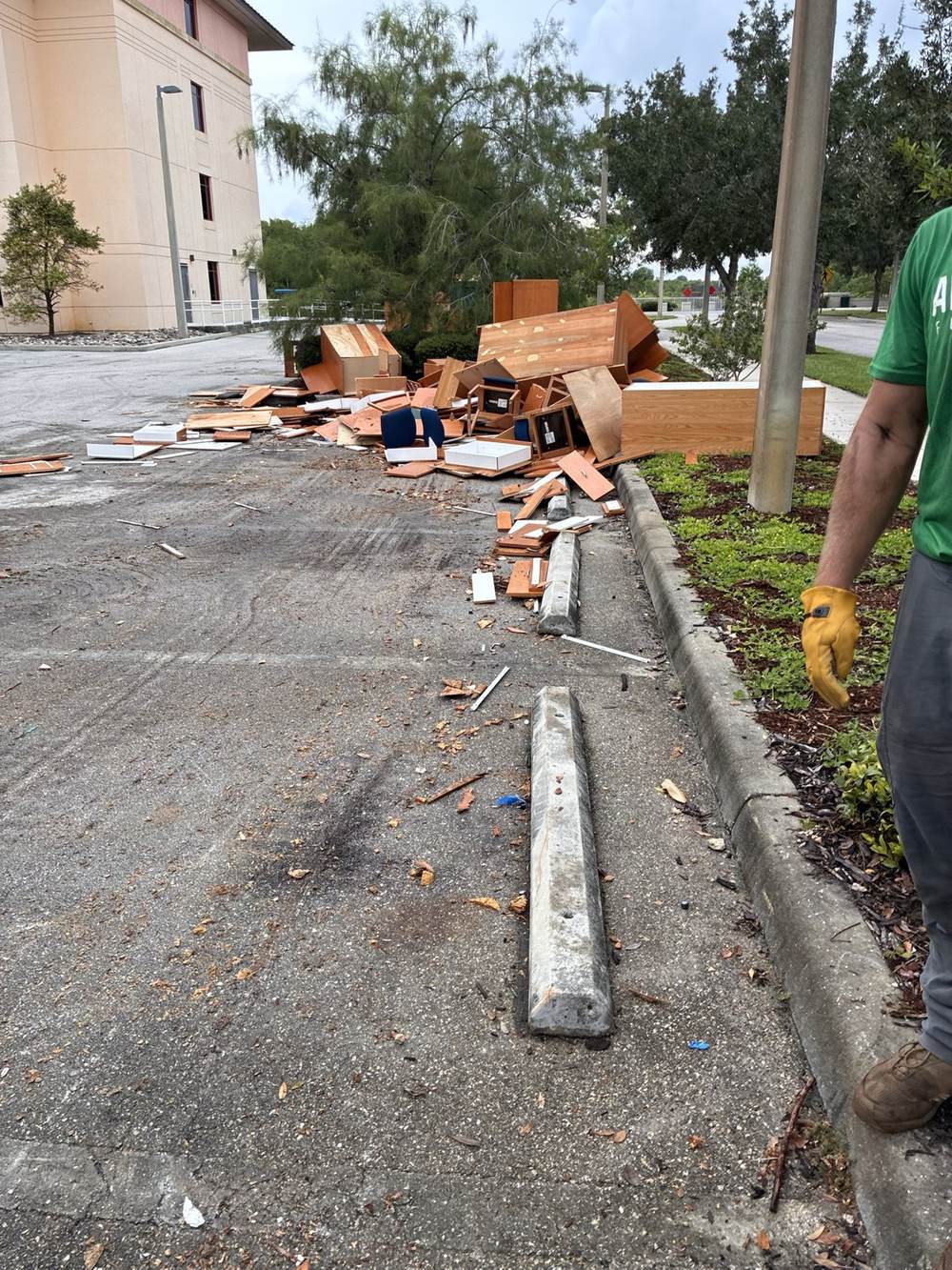 Pile of broken office furniture in a commercial parking lot in Southwest Florida, with a crew member in work gloves ready to haul it